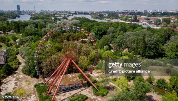 May 2018, Germany, Berlin: A ferris wheel standing in the former GDR amusement 'Spreepark' looms over the Plaenterwald area. The abandoned park is to...