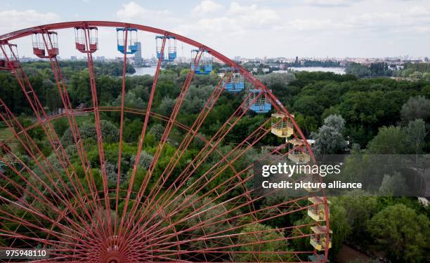 May 2018, Germany, Berlin: A ferris wheel standing in the former GDR amusement 'Spreepark' looms over the Plaenterwald area. The abandoned park is to...