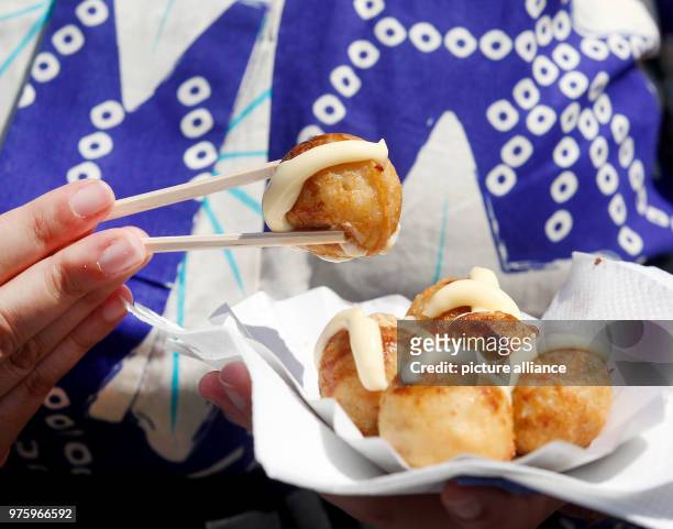May 2018, Germany, Duesseldorf: A Japanese woman eats fresh takoyaki, savory octopus balls, at the 17th Japan Day festivities. With its 7000 members,...