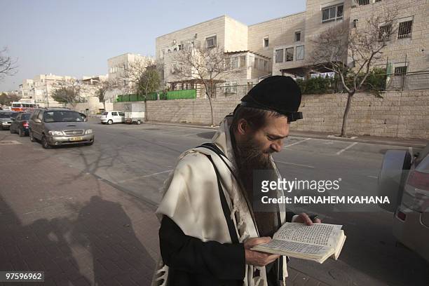 An ultra-Orthodox Jewish man prays as he walks in the streets of Ramat Shlomo, a Jewish settlement in the mainly Arab eastern sector of Jerusalem, on...