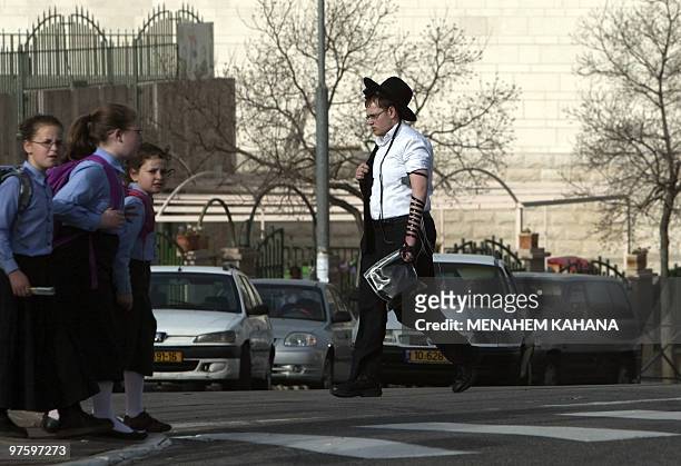 Israeli school girls wait to cross a street past a religious Jewish youth in Ramat Shlomo, a Jerusalem Jewish settlement, on March 10, 2010. Israel...