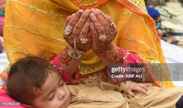 Pakistani Muslim worshipper holds her child as she prays to mark Eid al-Fitr at the Badshahi Mosque in Lahore on June 16, 2018. - Muslims around the...