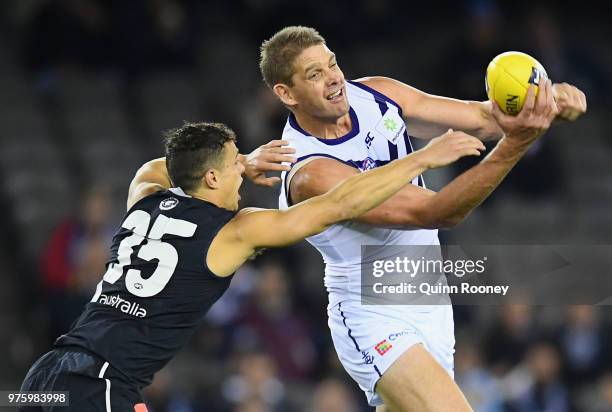 Aaron Sandilands of the Dockers handballs whilst being tackled by Ed Curnow of the Blues during the round 13 AFL match between the Carlton Blues and...