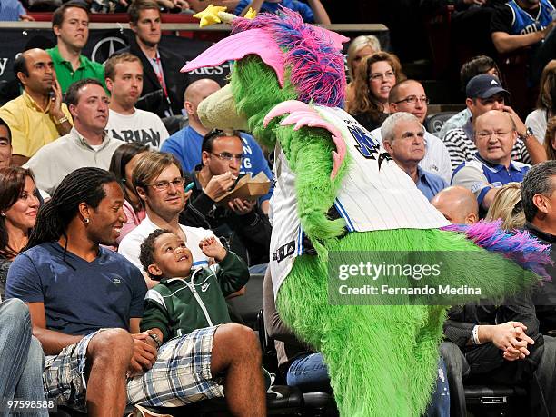 Larry Fitzgerald of the Phoenix Cardinals smiles as he sits courtside with his son Devininteracting with Magic mascot "Stuff" during the game between...