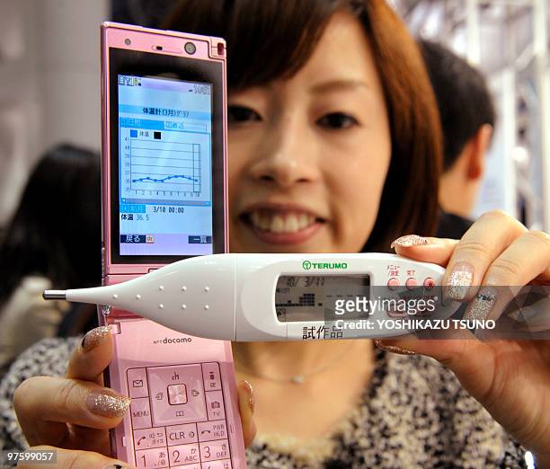 An employee for Japan's electronics company Sony displays the prototype model of a thermometer equipped with Sony's smart card Felica Plus chip,...