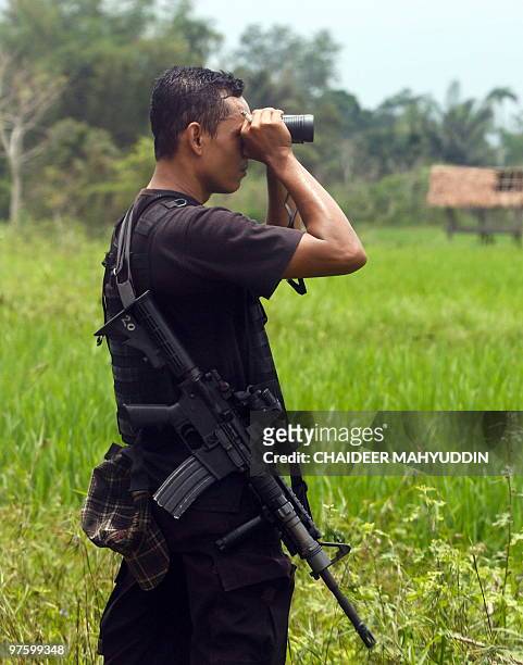 An Indonesian anti-terror policeman searches for terror suspects in Ayon, Aceh Besar on March 10 following a raid on Islamist militants. Indonesian...