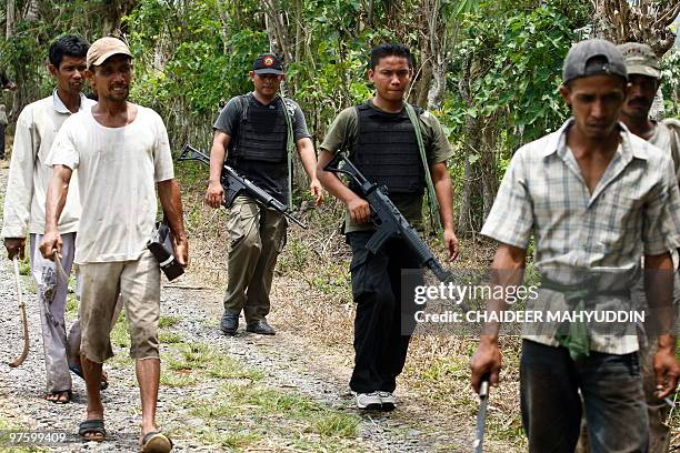 An Indonesian anti-terror policemen and villagers search for terror suspects in Ayon, Aceh Besar on March 10 following a raid on Islamist militants....