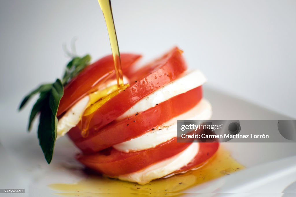 Oil on caprese salad with pepper.