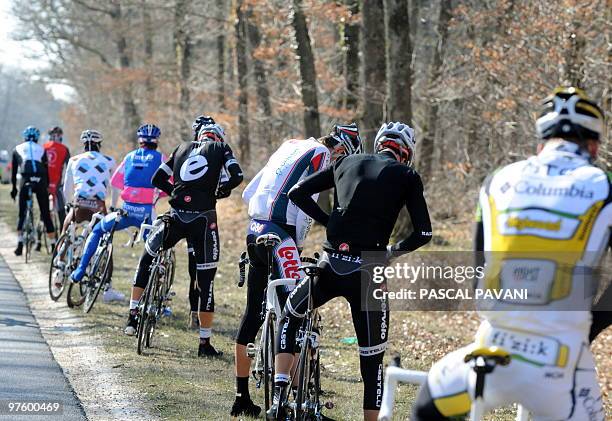 Cyclists relieve themselves on March 9, 2010 in the 201 km third stage of the 2010 Paris-Nice cycling race run between Contres and Limoges, center...