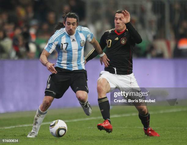 Lukas Podolski of Germany battles for the ball with Jonas Gutierrez of Argentina during the International Friendly match between Germany and...