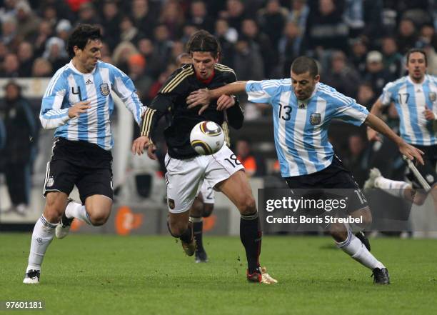 Mario Gomez of Germany battles for the ball with Nicolas Burdisso and Walter Samuel of Argentina during the International Friendly match between...