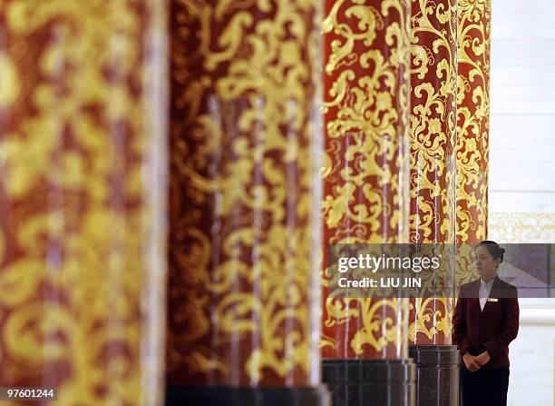 Hostess peers from behind the pillars during a press conference at the National People's Congress inside the Great Hall of the People in Beijing on...