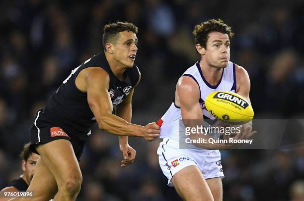Lachie Neale of the Dockers handballs whilst being tackled by Ed Curnow of the Blues during the round 13 AFL match between the Carlton Blues and the...