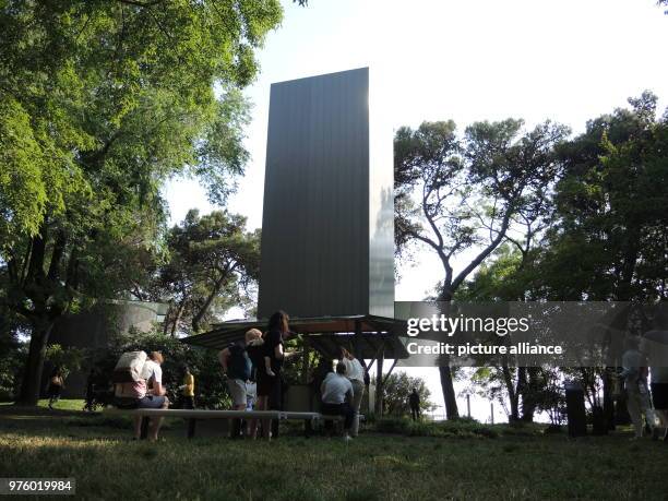 May 2018, Italy, Venice: Visitors sit in front of one of ten chapels on the island of San Giorgio Maggiore, designed by ten architects from around...