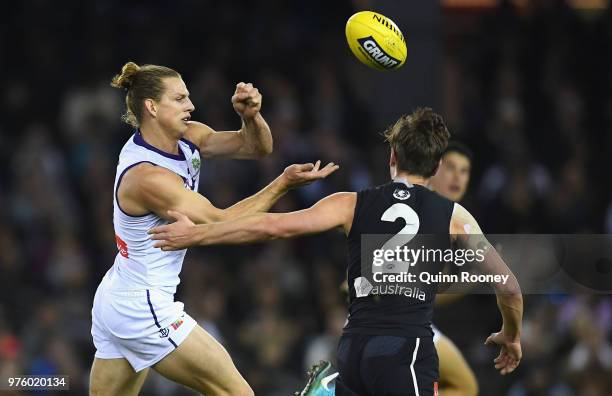 Nat Fyfe of the Dockers handballs whilst being tackled by Paddy Dow of the Blues during the round 13 AFL match between the Carlton Blues and the...