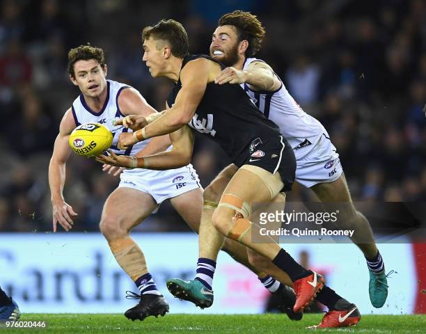 Patrick Cripps of the Blues handballs whilst being tackled by Connor Blakely of the Dockers during the round 13 AFL match between the Carlton Blues...