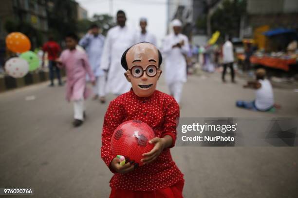 Dhaka, Bangladesh. A Bangladeshi girl wears mask as she celebrates Eid-ul-Fitr festival in Dhaka, Bangladesh on June 16, 2018. Muslims around the...