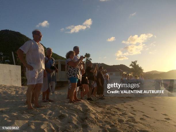 People stand on the beach in tribute to the late French rock singer Johnny Hallyday on June 15, 2018 in front of the Lorient cemetery on the French...