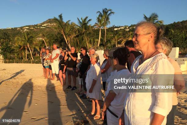 People stand on the beach in tribute to the late French rock singer Johnny Hallyday on June 15, 2018 in front of the Lorient cemetery on the French...