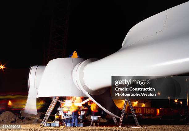 Long exposure shot at night of a worker assembling the hub and blades of a giant Enercon wind turbine in preparation for assembly on site Worksop...