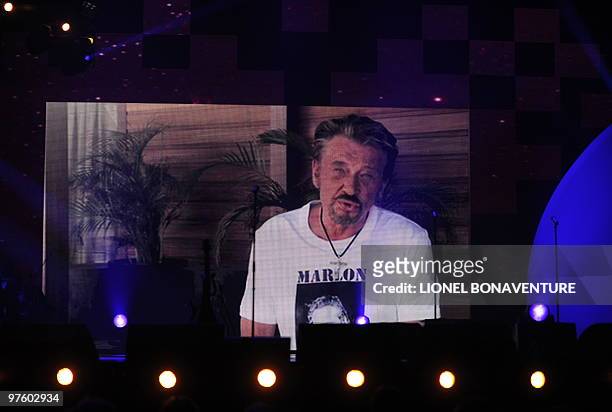 French singer Johnny Hallyday is seen on a giant screen as he couldn't attend the 25th Victoires de la Musique yearly French music awards ceremony on...