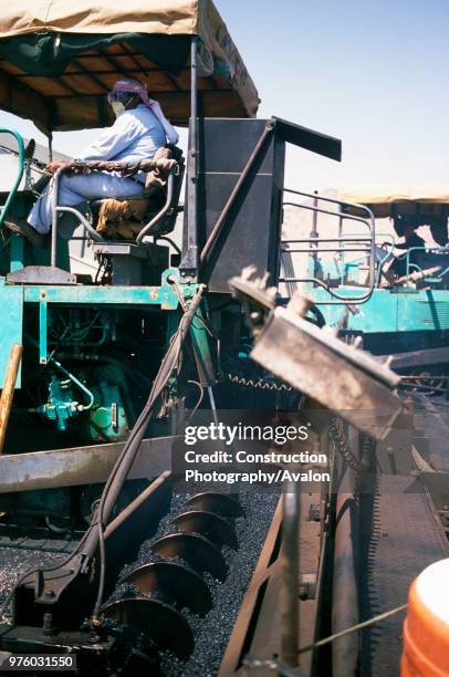 Guiding the paving machines for the endless asphalting - the hot asphalt in the hopper smokes as the screw delivery system pushes it out onto the...