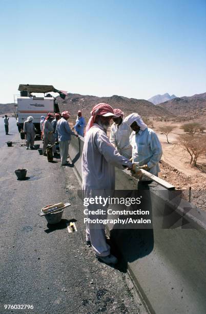 Slipforming road barrier on the Medina Yanbu section - trowel finishing work on the still wet concrete -- Jeddah to Medina highway, Saudi Arabia.