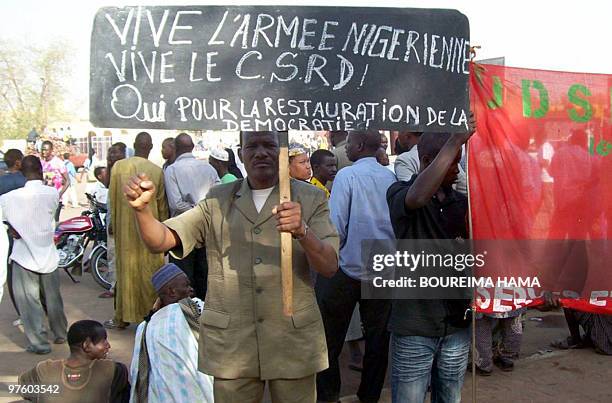 Man holds a banner reading 'Long life to Niger's army. Long life to CSRD. Yes to the restauration of democracy' during a rally in Niger's capital...