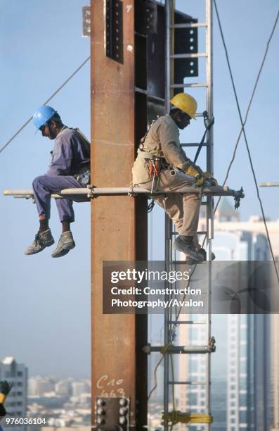 Workers sitting on scaffolding pole Steel frame work on the Gateway building for the new financial zone, Dubai Finance District, UAE.