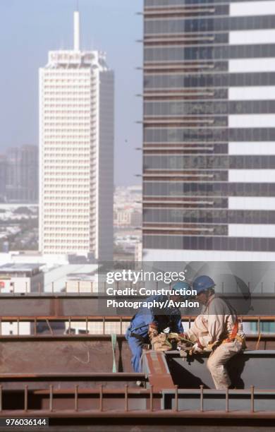 Construction workers on the Gateway building for the new financial zone - Dubai World Trade Centre in background Dubai Finance District, UAE.