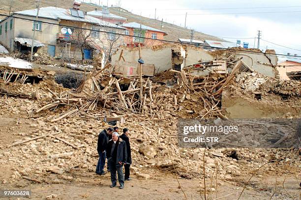 Turkish villagers wait near their destroyed houses in the village of Okcular in Elazig province on March 8, 2010. At least 57 people have been killed...