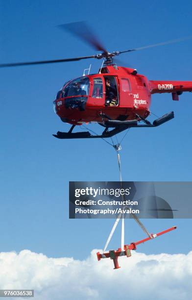 Helicopter delivers steel parts for a helicopter landing platform being built on an inaccessible lighthouse tower at the Needles, Isle of Wight,...