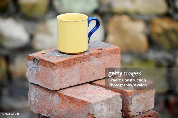 Builders mug of tea on a stack of reclaimed red bricks UK.