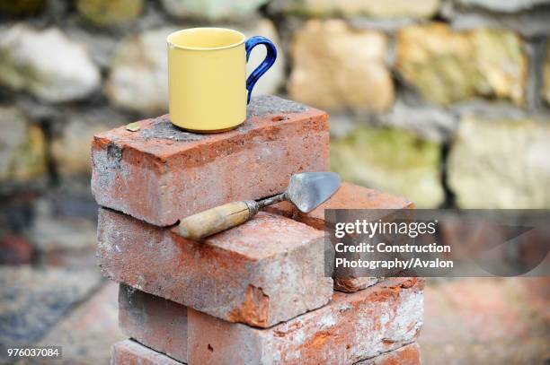 Builders mug of tea on a stack of reclaimed red bricks UK.