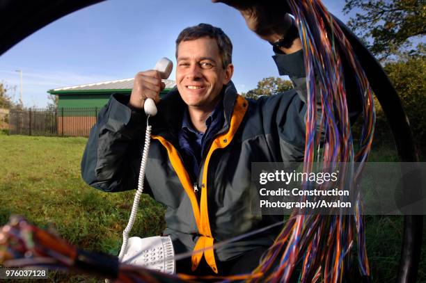 Telecommunications network designer with telephone cables at an exchange, UK.