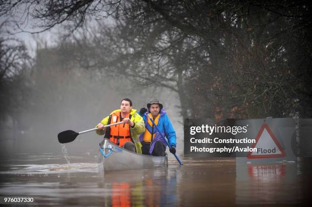 Two people canoeing past flood sign during floods, Gloucestershire, UK, 2007.