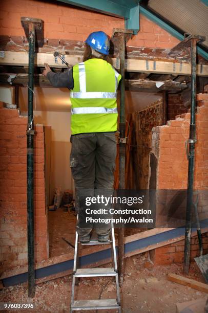 Workman fixes joist straps with acrow props and strong boys holding a supporting wall before a rsj is fitted to allow the enlargement of a wall...