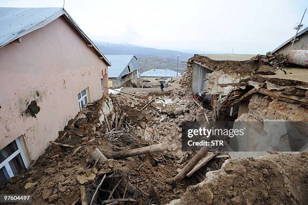 Man walks past debris of a destroyed house in the village of Okcular, on March 8, 2010. A powerful pre-dawn earthquake buried sleeping villagers in...