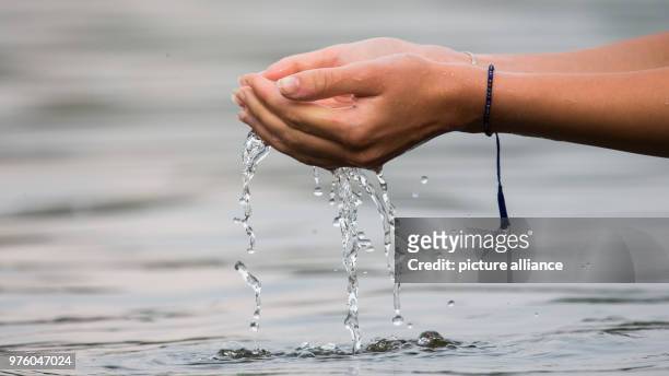 Niedersachsen, Oldenburg: Eine Frau steht im Woldsee und lässt Wasser durch ihre Hände laufen Photo: Mohssen Assanimoghaddam/dpa