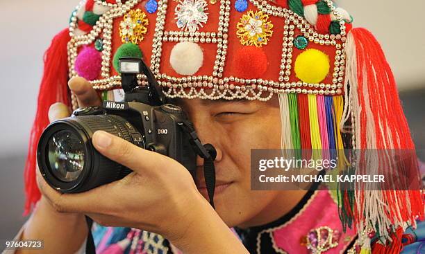 Man from Taiwan wearing traditional clothes takes a photo at the ITB travel trade fair at the fair grounds in Berlin, on March 10, 2010. The...