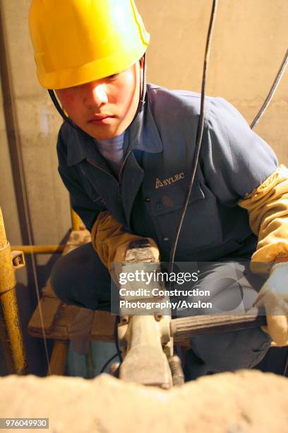 Chinese worker drills inside the lift shaft of an office tower under construction in Beijing.