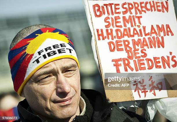 Man holds up a placard which reads "Please speak with the Dalai Lama, the man of peace" as he takes part in a protest rally at the Chinese embassy in...