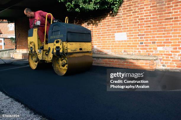 Spreading and rolling hot asphalt using vibratory roller .