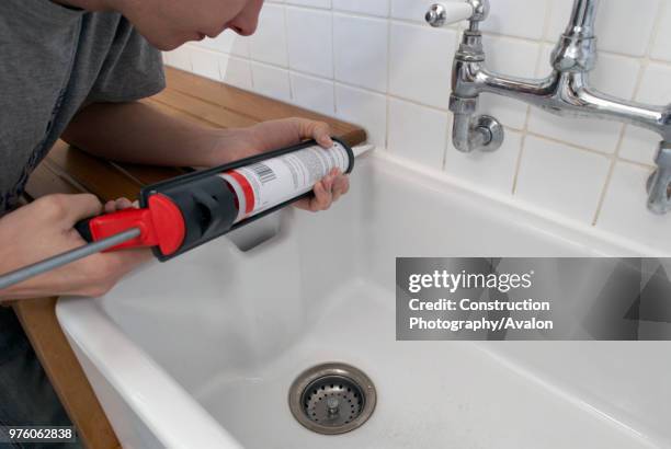 Man using sealant gun in bathroom.