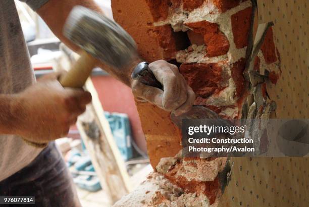 Man removing brick wall of house, UK.