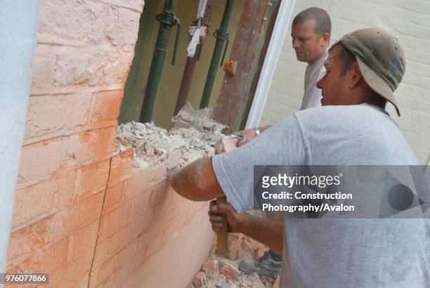 Man removing brick wall of house, UK.