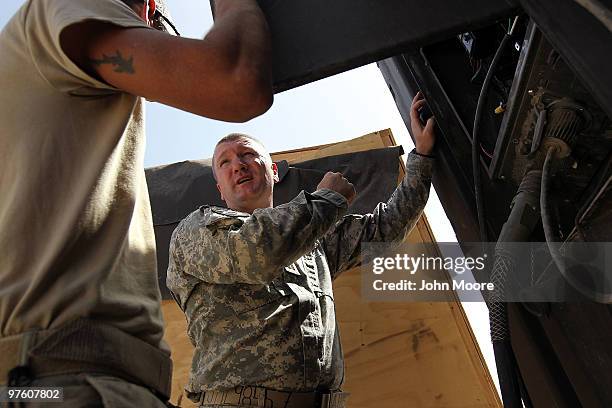 Army Chaplain Cpt. Kevin Burton , helps Ssg. Isaac Cunningham with a circuit breaker at Combat Outpost Terminator on March 10, 2010 in Kandahar...