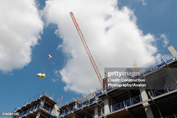 Crane lifting a delivery of sacks of sand and cement on a development, London, UK.