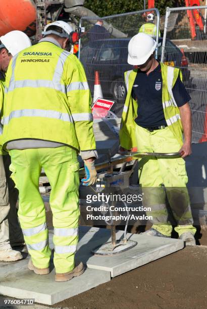 Construction workers using paving stone layer at Westfield London Shopping Centre, Shepherds Bush, London UK.