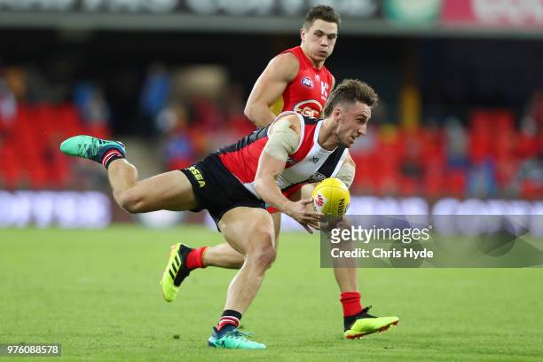 Luke Dunstan of the Saints handballs during the round 13 AFL match between the Gold Coast Suns and the St Kilda Saints at Metricon Stadium on June...